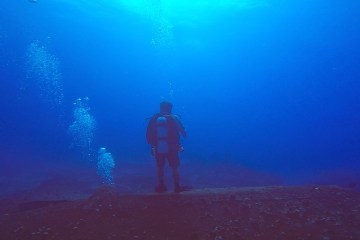 Scuba diver standing on underwater wreck in Oahu, Hawaii